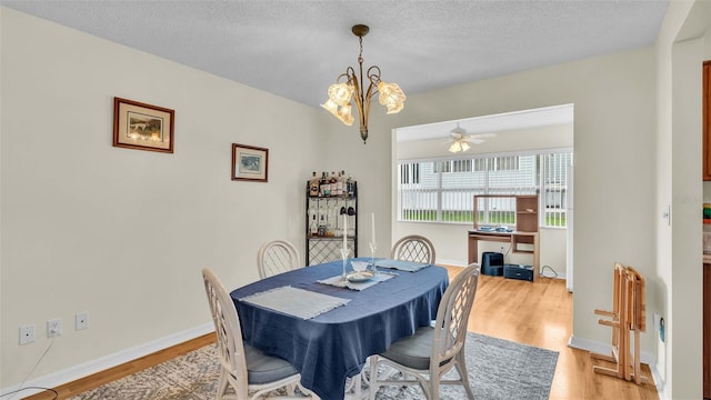 dining area with ceiling fan with notable chandelier, a textured ceiling, and light wood-type flooring