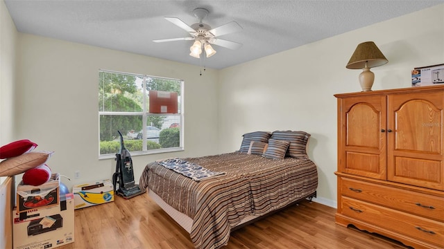 bedroom with ceiling fan, a textured ceiling, multiple windows, and light wood-type flooring