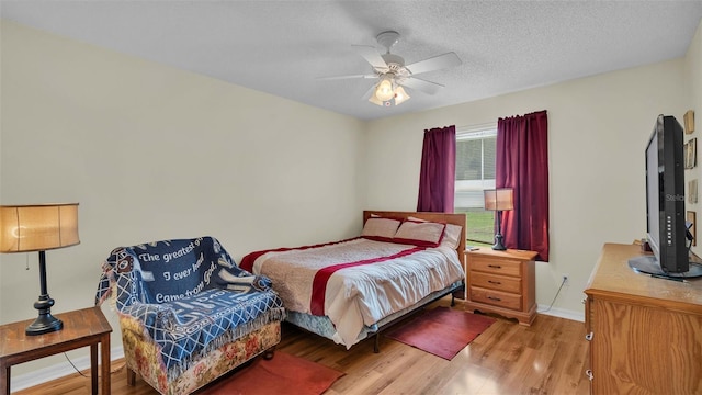 bedroom featuring ceiling fan, light hardwood / wood-style flooring, and a textured ceiling