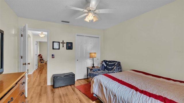 bedroom with a textured ceiling, a closet, ceiling fan, and light wood-type flooring