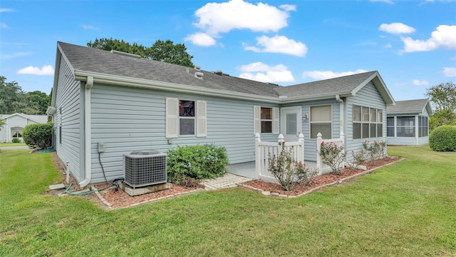 back of house with a sunroom, central AC, and a lawn