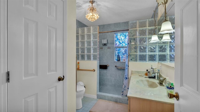 bathroom with vanity, tiled shower, toilet, tile patterned floors, and a textured ceiling