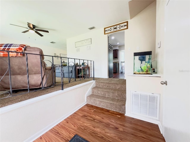 staircase featuring ceiling fan and hardwood / wood-style flooring