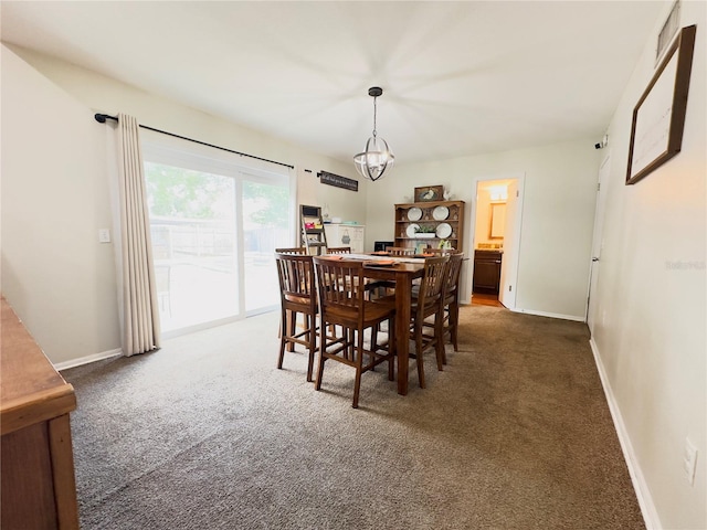 dining space featuring an inviting chandelier and dark colored carpet