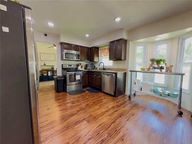 kitchen with light hardwood / wood-style floors, appliances with stainless steel finishes, dark brown cabinetry, and sink