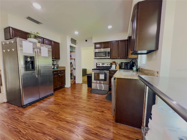 kitchen featuring dark brown cabinets, stainless steel appliances, light wood-type flooring, and sink