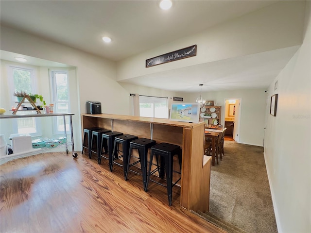 kitchen with a wealth of natural light, a kitchen bar, and light wood-type flooring