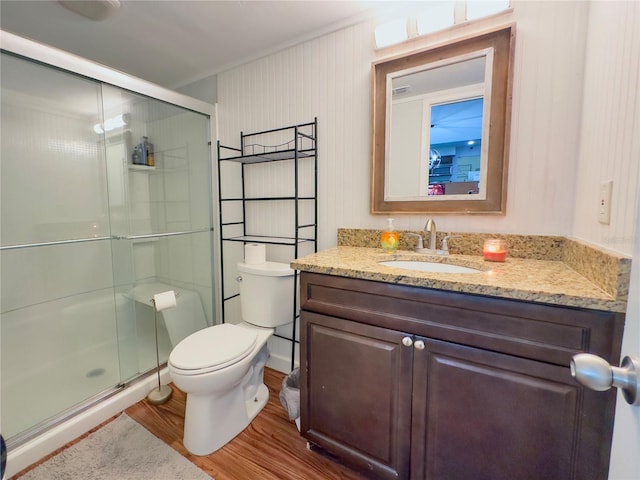 bathroom with wood-type flooring, vanity, a shower with shower door, and toilet