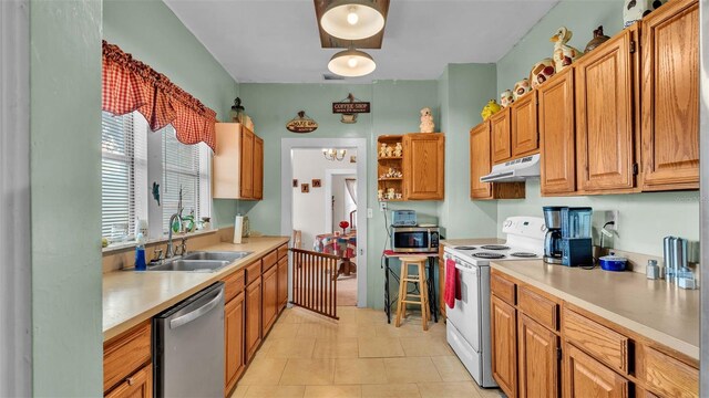 kitchen featuring light tile patterned flooring, stainless steel appliances, a chandelier, and sink