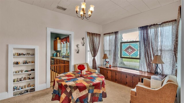 dining room with sink, a chandelier, and light colored carpet