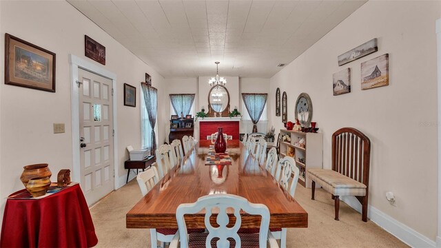 dining room with light carpet and a chandelier