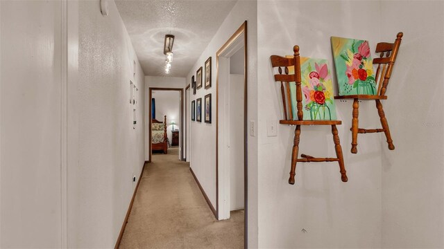 hallway featuring a textured ceiling and light colored carpet