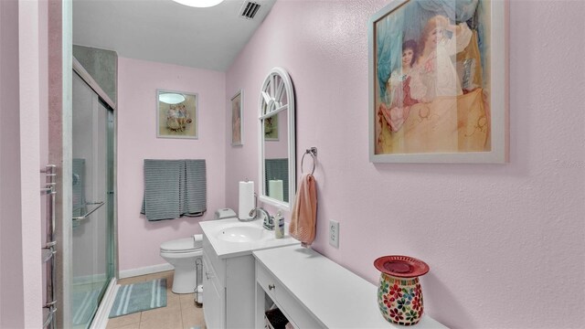 bathroom featuring tile patterned flooring, a shower with door, toilet, and vanity