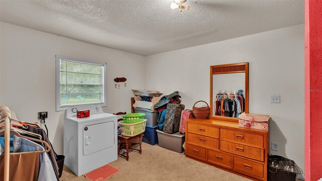 laundry area with a textured ceiling, light carpet, and washer / dryer