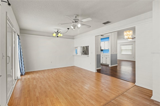 unfurnished living room with a textured ceiling, light hardwood / wood-style flooring, and ceiling fan with notable chandelier