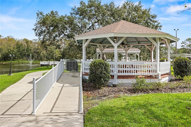 view of property's community with a gazebo, a water view, and a lawn