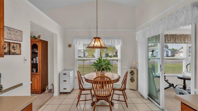 tiled dining room with ornamental molding, lofted ceiling, and a healthy amount of sunlight