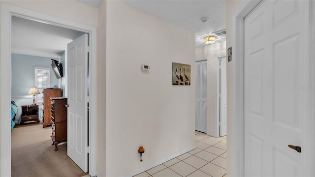 corridor featuring light colored carpet and a textured ceiling