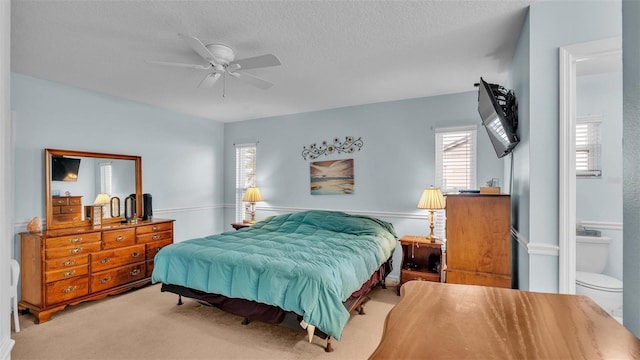 carpeted bedroom featuring connected bathroom, ceiling fan, and a textured ceiling