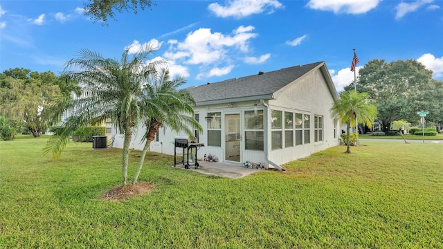 rear view of property with cooling unit, a yard, and a sunroom