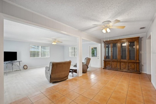 tiled living room with a textured ceiling, ornamental molding, and ceiling fan