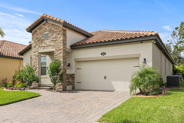 mediterranean / spanish-style home featuring a front yard, cooling unit, and a garage