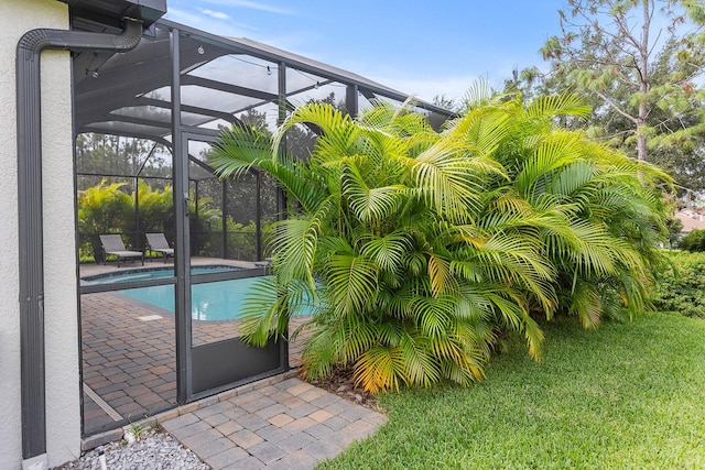 view of pool with a yard and glass enclosure