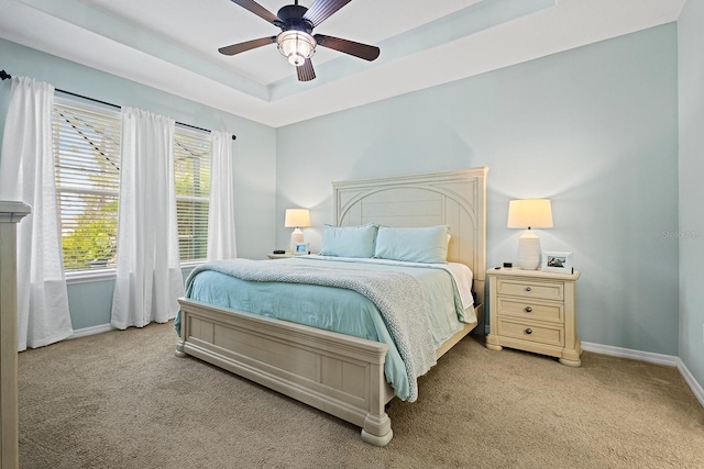 bedroom with a raised ceiling, light carpet, and ceiling fan