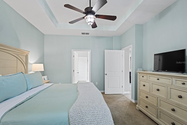 bedroom featuring light colored carpet, a raised ceiling, and ceiling fan