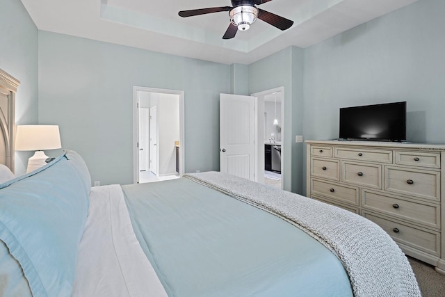 bedroom featuring ceiling fan, ensuite bath, and a raised ceiling