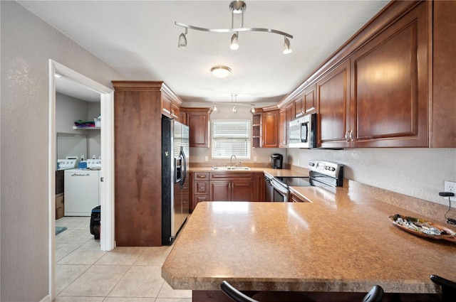 kitchen with light tile patterned flooring, sink, kitchen peninsula, rail lighting, and stainless steel appliances