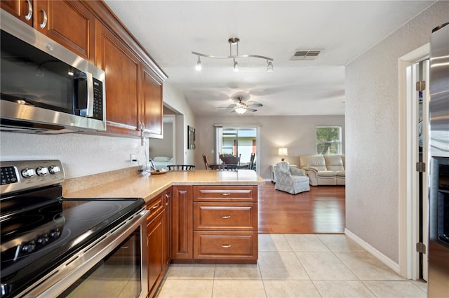 kitchen featuring ceiling fan, stainless steel appliances, light hardwood / wood-style floors, and kitchen peninsula