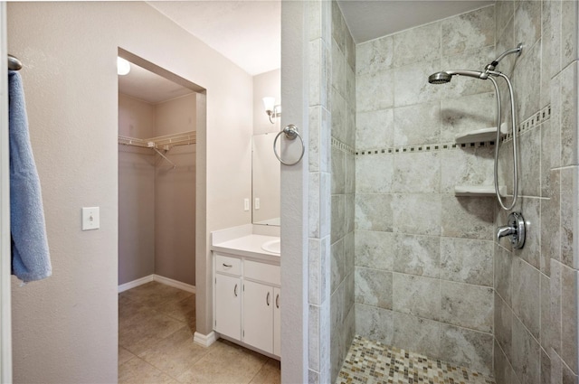 bathroom featuring tiled shower, vanity, and tile patterned flooring