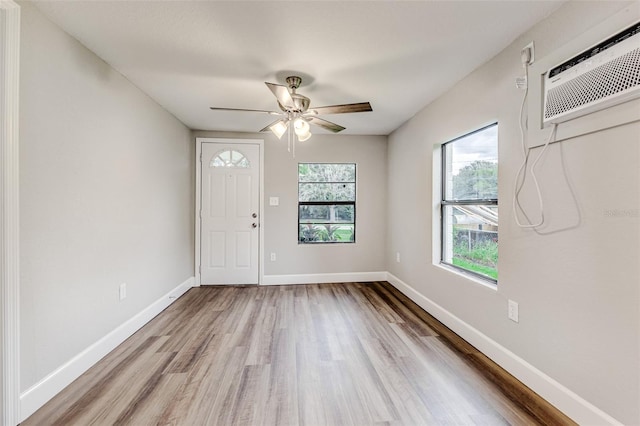 entryway with ceiling fan, a wall mounted air conditioner, and light hardwood / wood-style floors