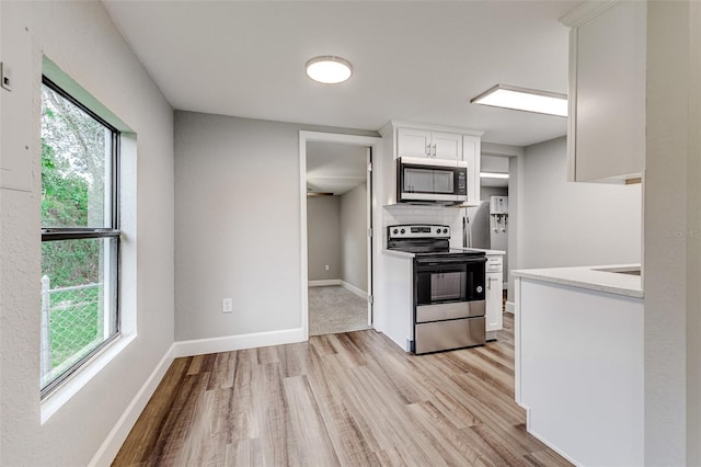 kitchen with light hardwood / wood-style flooring, white cabinets, appliances with stainless steel finishes, and plenty of natural light