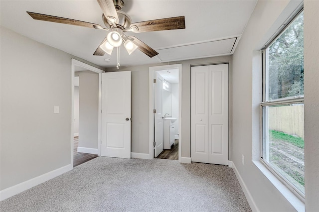 unfurnished bedroom with dark colored carpet, ceiling fan, and ensuite bathroom