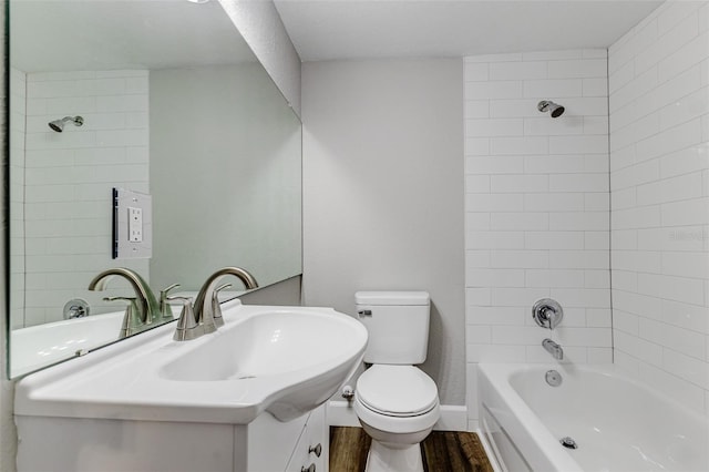 full bathroom with wood-type flooring, tiled shower / bath, vanity, and toilet