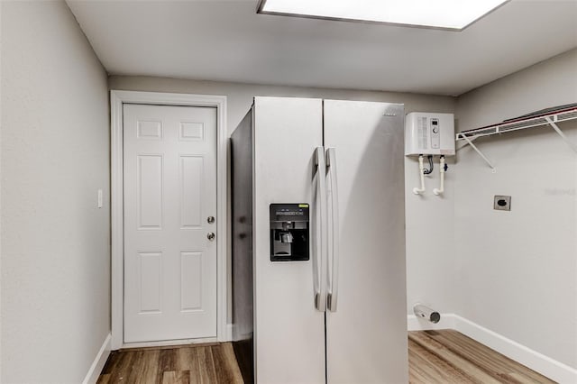 washroom featuring tankless water heater, electric dryer hookup, and hardwood / wood-style flooring