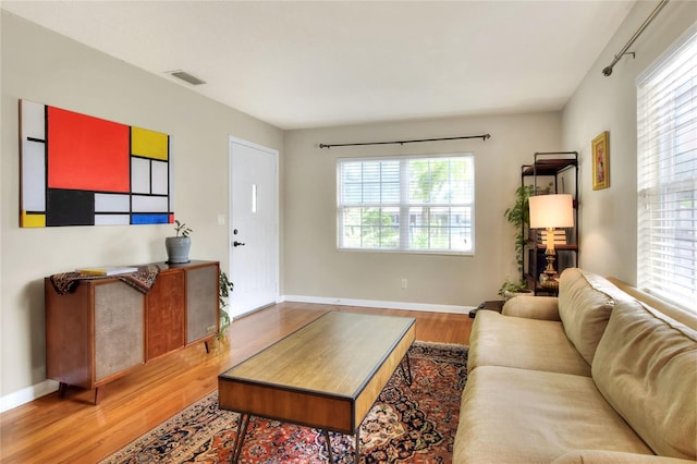 living room with wood finished floors, visible vents, and baseboards