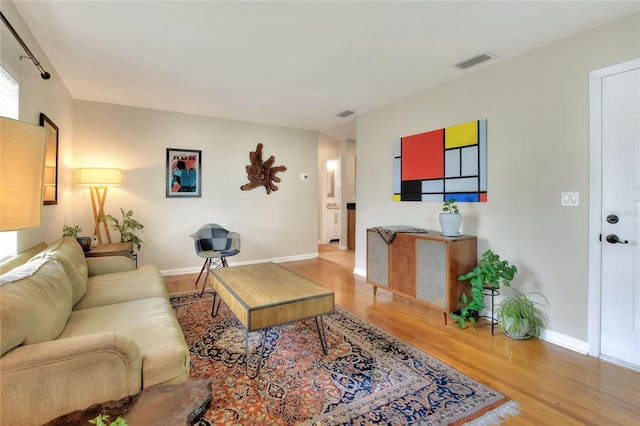 living room featuring wood finished floors, visible vents, and baseboards