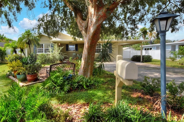 view of front of house featuring an attached carport, concrete driveway, and fence