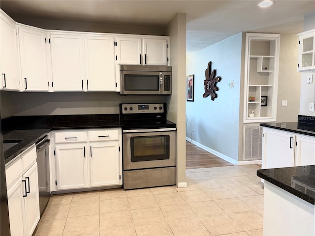 kitchen featuring stainless steel appliances, white cabinets, visible vents, and dark stone countertops