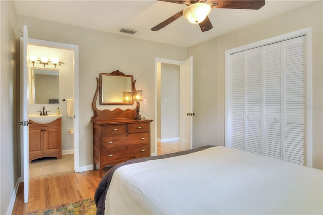 bedroom with a closet, visible vents, ensuite bathroom, light wood-style floors, and a sink