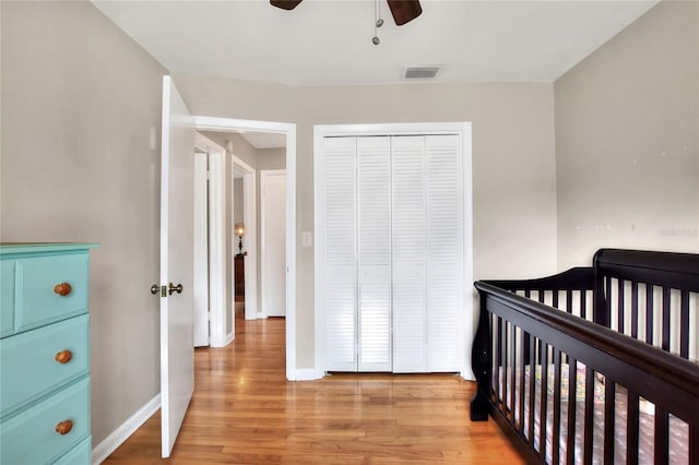 bedroom featuring light wood-style floors, a nursery area, a closet, and baseboards