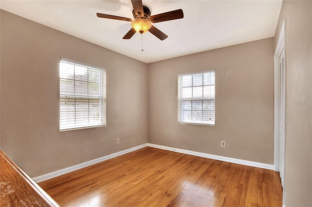 spare room featuring ceiling fan, baseboards, and wood finished floors