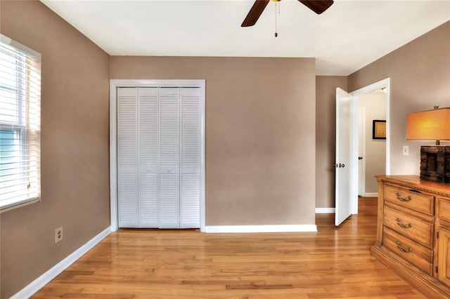 unfurnished bedroom with a ceiling fan, a closet, light wood-style flooring, and baseboards