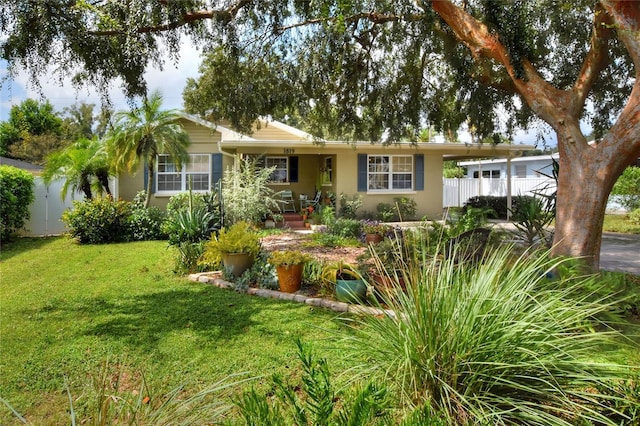 ranch-style home featuring a front yard, fence, and stucco siding