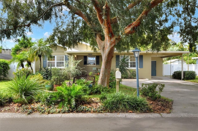 ranch-style house featuring a carport, concrete driveway, and fence