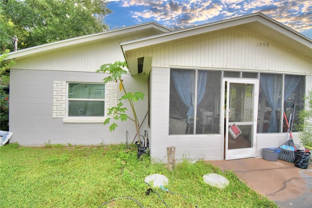 view of property exterior featuring a sunroom and a yard