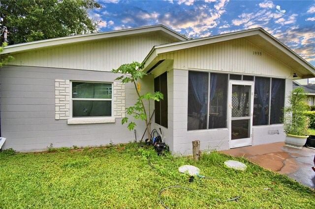 exterior space featuring a front lawn and a sunroom